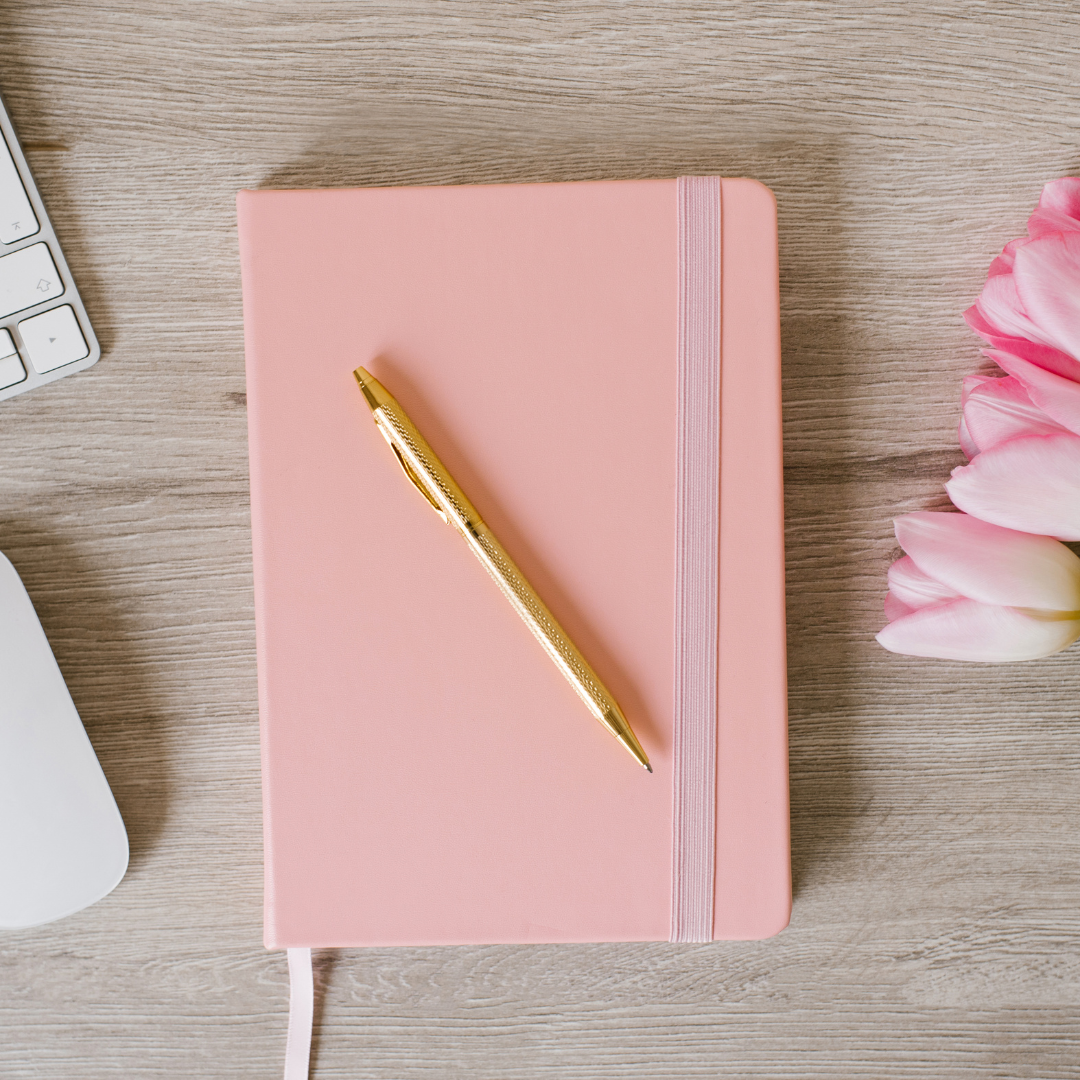 pink journal on desk with gold pen